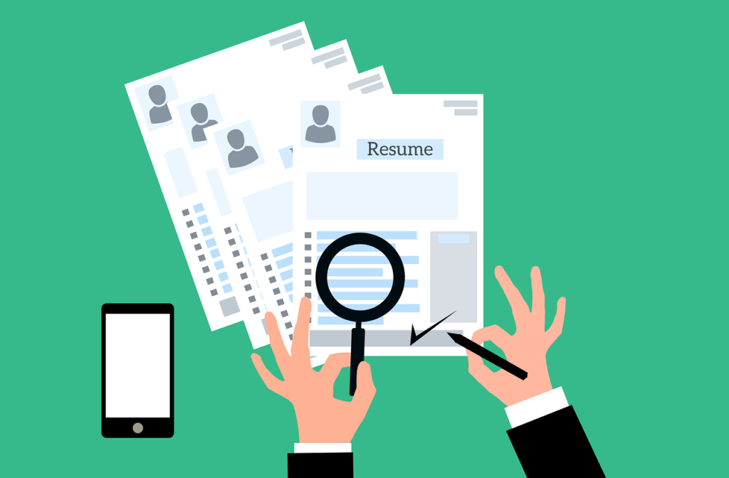 Somone who is looking at resumes. They have a magnifying glass over one of the resumes and tick this resume